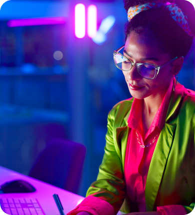 Une femme en veste verte concentrée sur son ordinateur, engagée dans des activités de trading de forex.