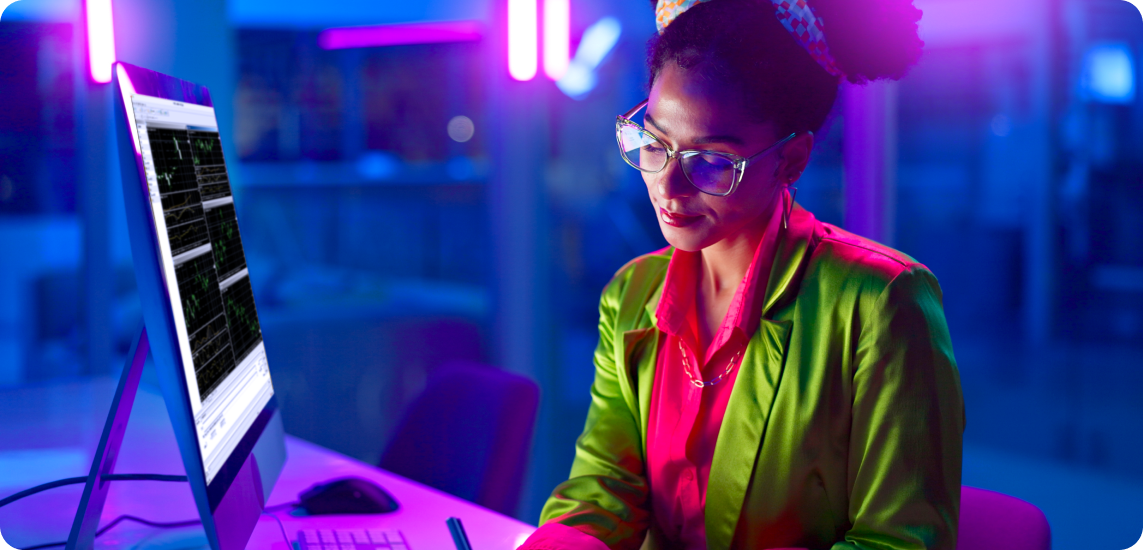 Une femme en veste verte concentrée sur son ordinateur, engagée dans des activités de trading de forex.