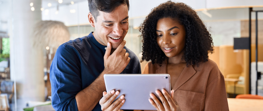 A man and woman traders collaborating on forex analysis, examining information displayed on a tablet platform.