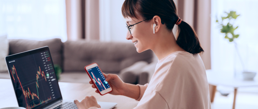 Un trader en costume est assis par terre avec un ordinateur portable, entouré par un symbole dollar, représentant des activités de trading et financières. 