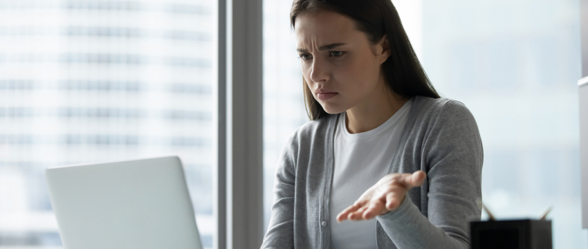 A woman at a desk with a laptop, engaged in forex trading error analysis.